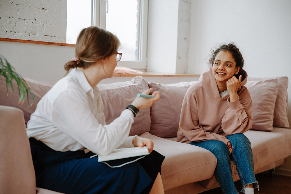 two young women talking on a couch