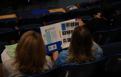 photo from behind two women seated looking at informational folder