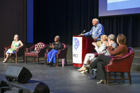 older man in blue shirt speaking at a podium