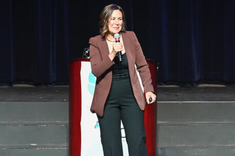 woman in brown and black outfit speaking on stage