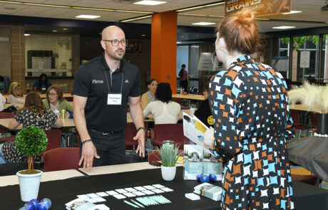 man in black shirt speaking to woman as plena table
