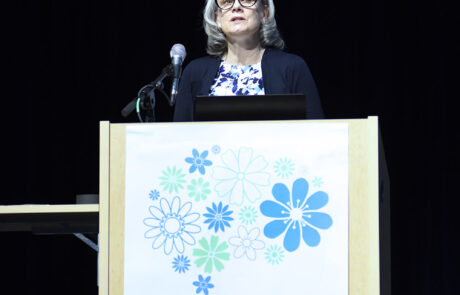 woman with glasses on stage behind a podium