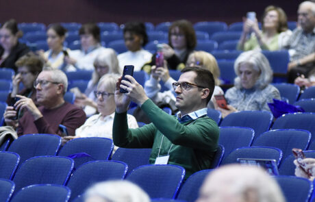 man in green shirt using phone to scan QR code