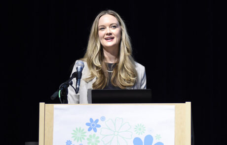 woman speaking on stage behind a podium