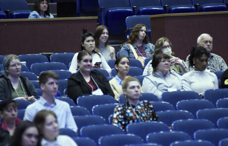people sitting in blue chairs in auditorium