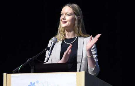 woman speaking on stage behind a podium