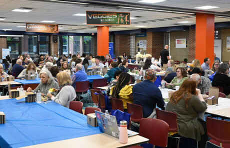 people eating and talking in a large cafeteria