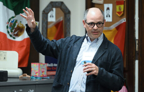man with glasses speaking while elevating his right arm