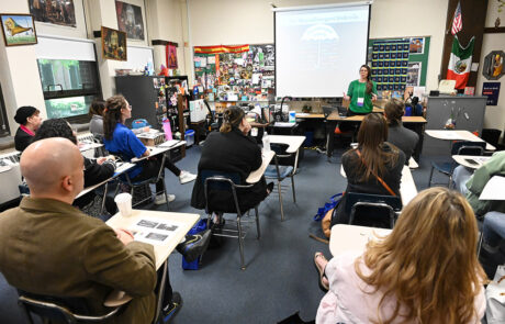 woman in green shirt speaking to classroom of people