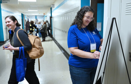 woman in blue shirt writing look at poster display