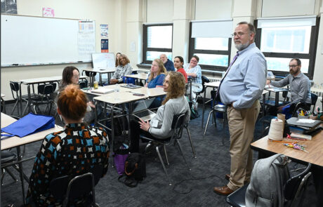 man in light blue button shirt standing in the middle of a classroom