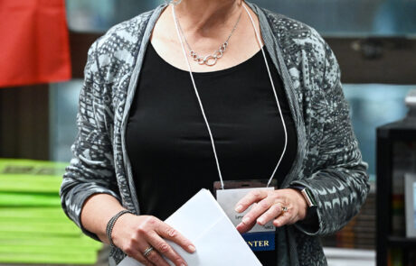 woman with short hair and glasses holding papers