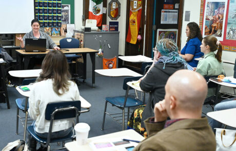 woman at desk in classroom with a laptop