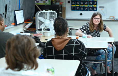 woman in glasses look at people sitting at desks